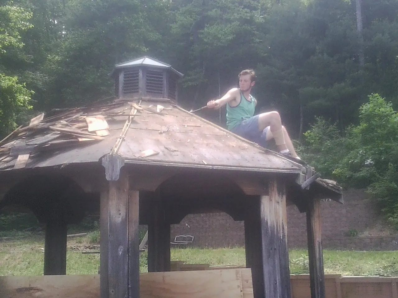 Tearing the old roof off a wooden gazebo before new shakes in Helmville