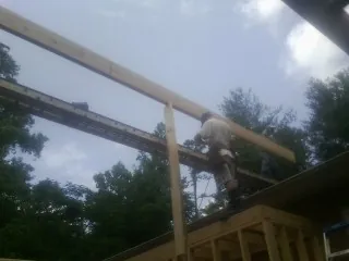 Carpenter setting a ridge beam over a new addition frame — Ice Dam Removal by Roofing Brothers in Helmville