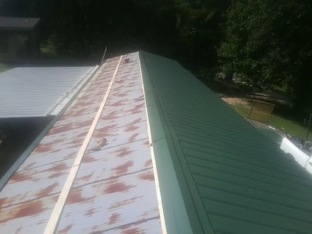 Old rusted panels beside newly installed green metal roofing — Wind Damage Roof Repair by Roofing Brothers in Helmville