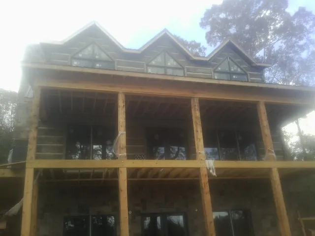 Dormers and porch framing on a large log home under construction — Roof Coating work by our crew in Helmville