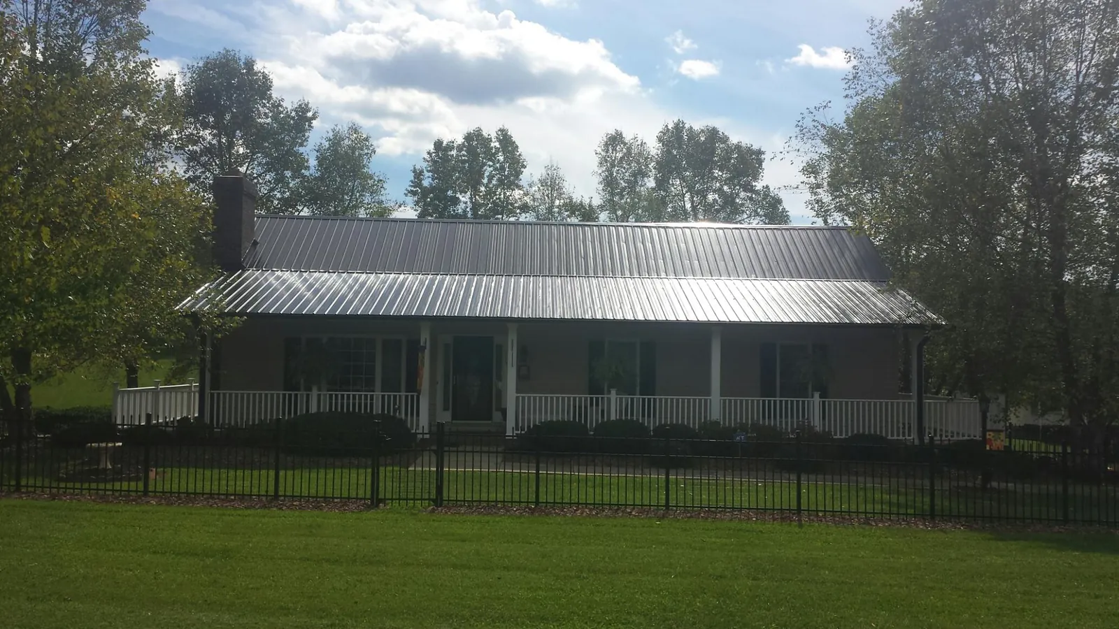 Gray metal roof on a brick ranch with a full width front porch — Gutter Guard Installation work by our crew in Helmville
