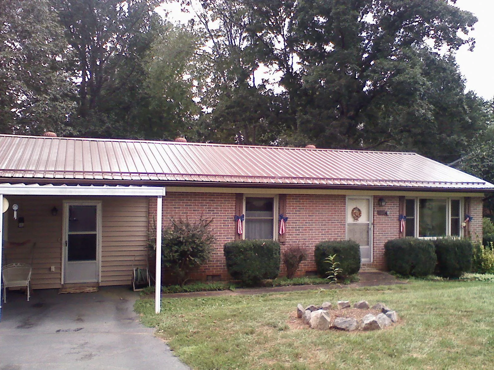 Bronze metal roof and carport on a brick ranch home — Roof Repair work by our crew in Helmville