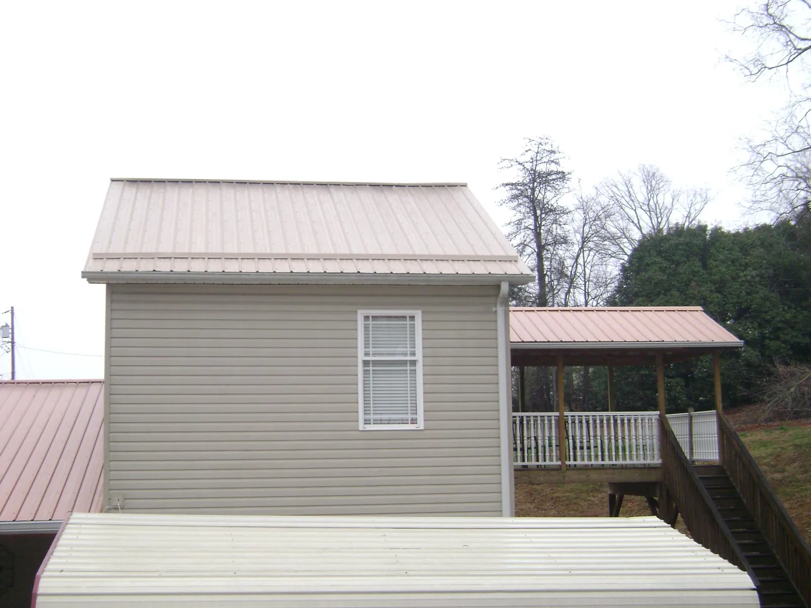 Tan metal roofs on a two story addition and attached porch, from a Roof Replacement job in Helmville
